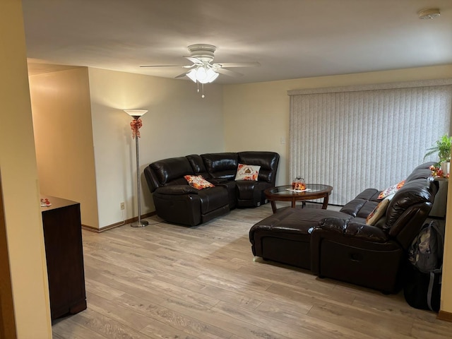 living area featuring ceiling fan, light wood-style flooring, and baseboards