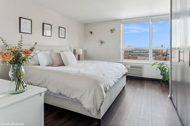 bedroom with an AC wall unit and dark wood-style flooring