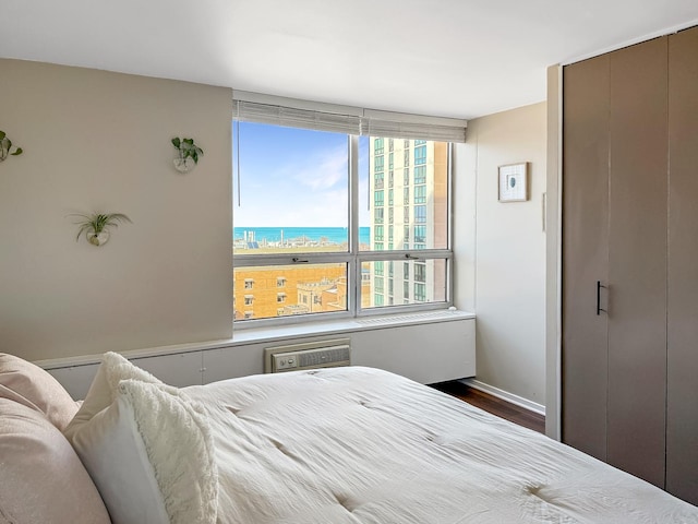 bedroom with dark wood finished floors, baseboards, and a wall unit AC