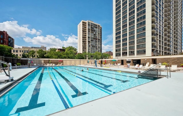 community pool featuring a city view, a patio area, and fence