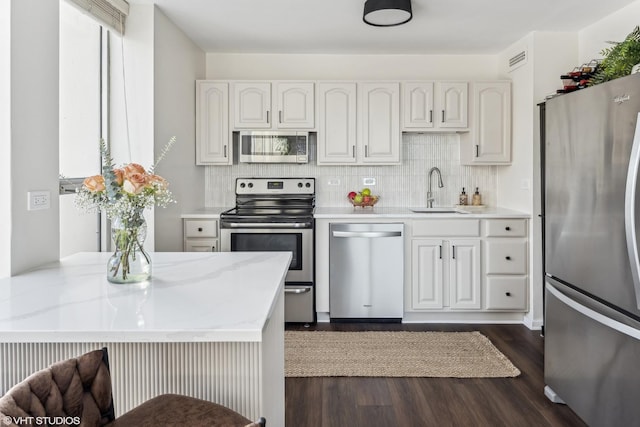 kitchen featuring tasteful backsplash, dark wood finished floors, appliances with stainless steel finishes, and a sink