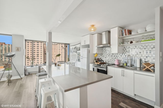 kitchen with electric range, a sink, white cabinets, wall chimney range hood, and open shelves