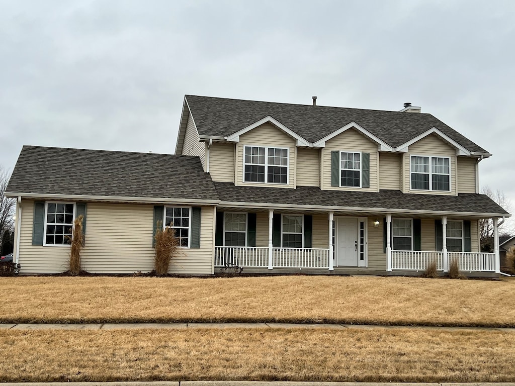 view of front facade featuring roof with shingles, a porch, and a front yard