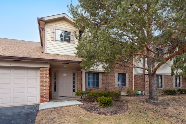 traditional home featuring driveway, brick siding, an attached garage, and a shingled roof