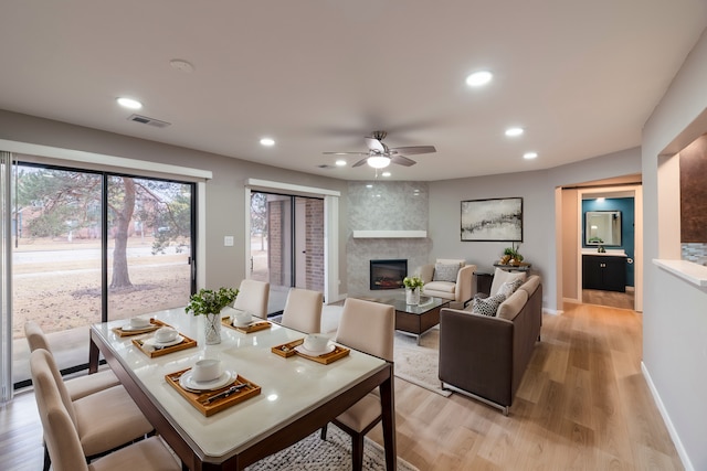 dining room with ceiling fan, a tile fireplace, recessed lighting, baseboards, and light wood finished floors