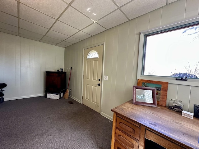 foyer featuring a drop ceiling and dark carpet