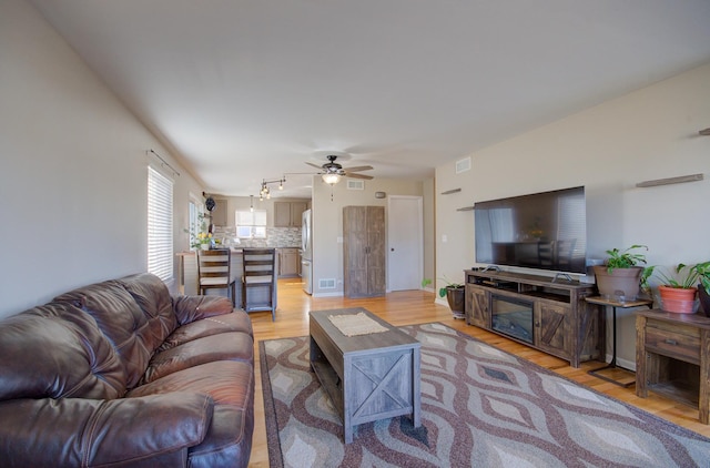 living room featuring visible vents, light wood-style floors, and a ceiling fan