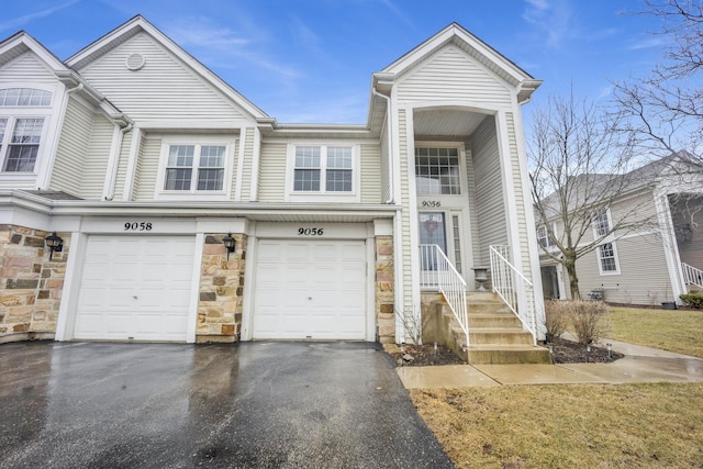 townhome / multi-family property featuring stone siding and driveway