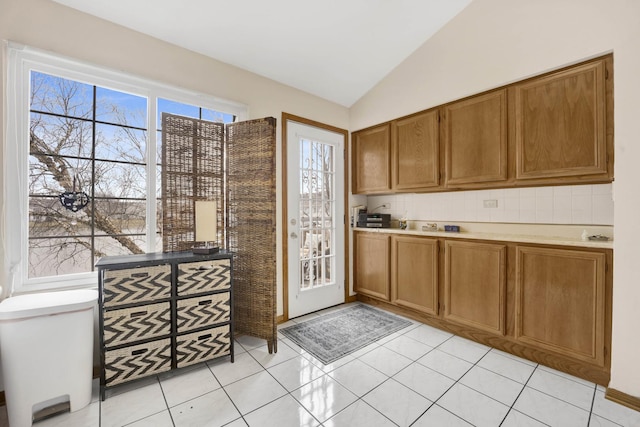 kitchen featuring brown cabinetry, light countertops, and vaulted ceiling