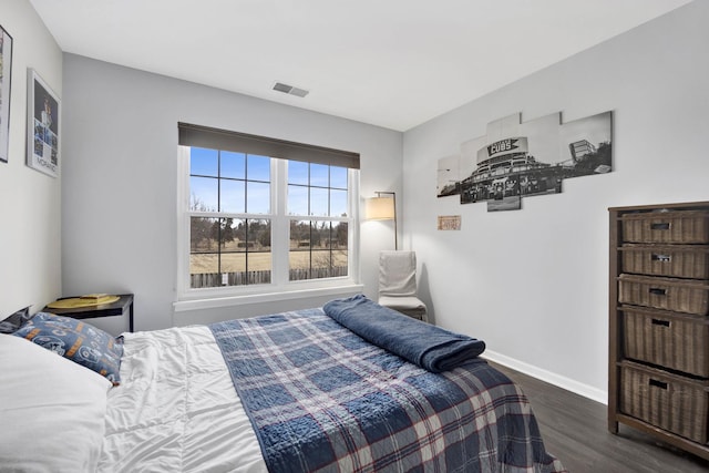 bedroom with baseboards, visible vents, and wood finished floors