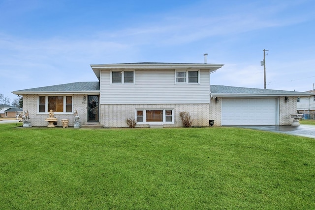 split level home with concrete driveway, roof with shingles, an attached garage, a front yard, and brick siding