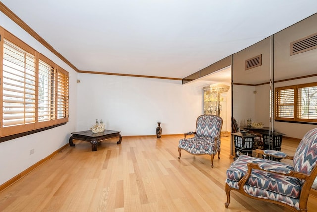 sitting room featuring baseboards, visible vents, ornamental molding, and wood finished floors