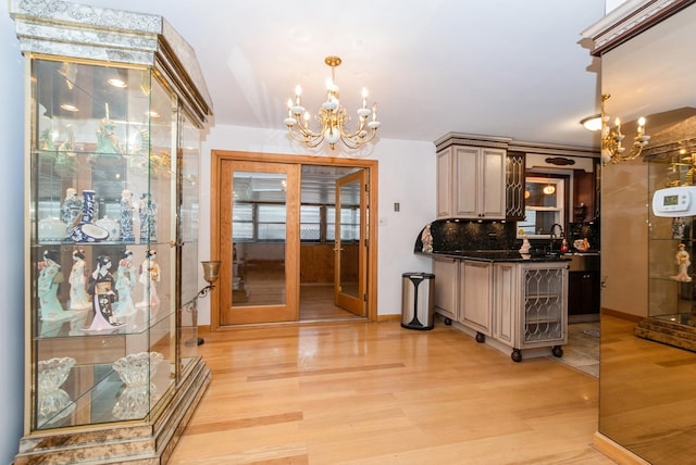 interior space featuring a chandelier, a sink, light wood finished floors, decorative light fixtures, and tasteful backsplash