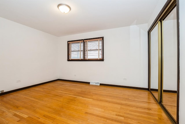 unfurnished bedroom featuring a closet, visible vents, light wood-style flooring, and baseboards