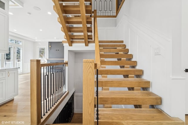 stairs featuring a wainscoted wall, recessed lighting, wood finished floors, and a decorative wall