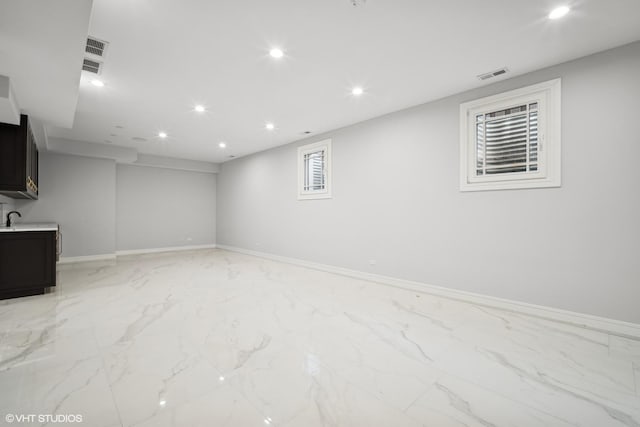 below grade area with marble finish floor, recessed lighting, visible vents, and baseboards