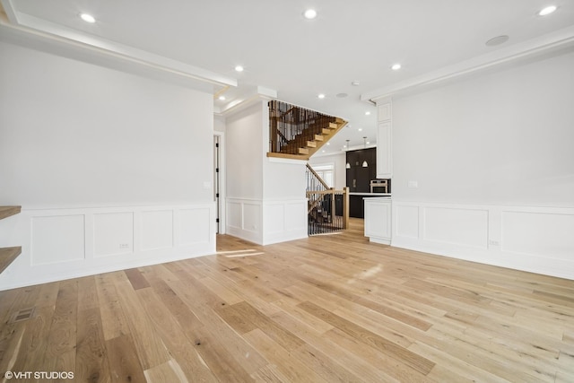 unfurnished living room featuring light wood finished floors, stairway, and recessed lighting