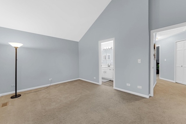 unfurnished bedroom featuring ensuite bath, carpet, high vaulted ceiling, and baseboards