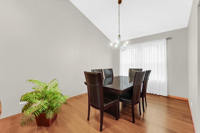 dining area with lofted ceiling, light wood-style floors, baseboards, and a notable chandelier