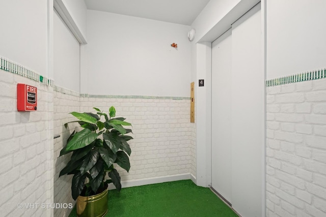 corridor featuring carpet flooring and a wainscoted wall