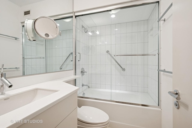 full bathroom featuring visible vents, toilet, vanity, and bath / shower combo with glass door