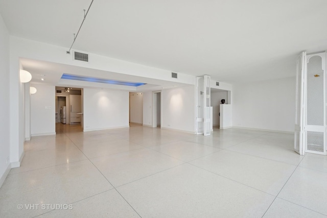 spare room featuring light speckled floor, visible vents, and baseboards