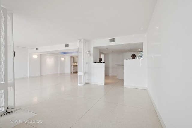 spare room with light speckled floor, visible vents, and baseboards