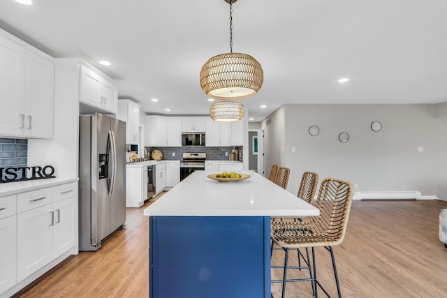 kitchen with light wood-style floors, appliances with stainless steel finishes, decorative backsplash, a center island, and a kitchen bar