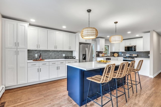 kitchen with stainless steel appliances, light wood finished floors, light countertops, and white cabinetry