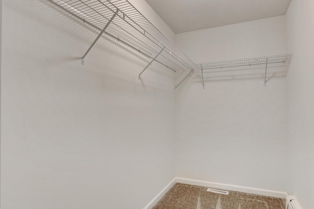 spacious closet featuring a baseboard radiator, carpet, and visible vents