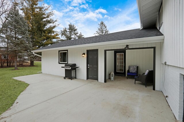 rear view of property with a shingled roof, a patio area, and a yard