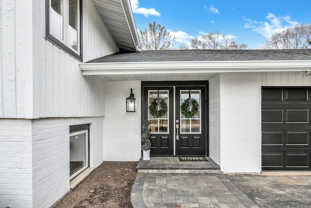 entrance to property featuring brick siding and roof with shingles