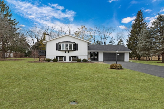 view of front facade with a garage, a chimney, aphalt driveway, and a front yard