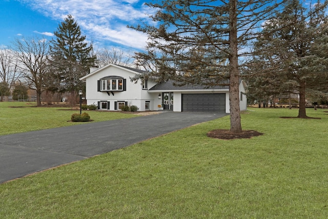 tri-level home featuring an attached garage, driveway, a chimney, and a front lawn