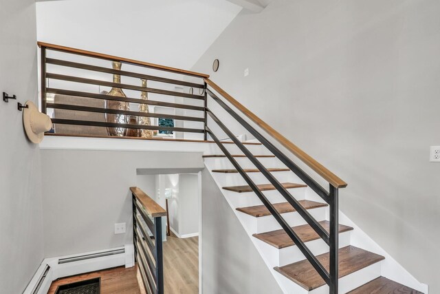 stairs featuring a baseboard radiator and wood finished floors