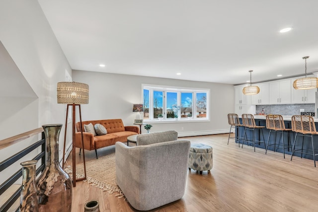 living room with baseboards, light wood finished floors, baseboard heating, and recessed lighting