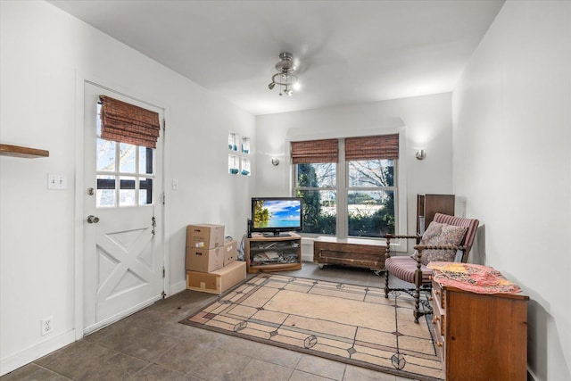 living area featuring tile patterned flooring, plenty of natural light, baseboards, and a ceiling fan