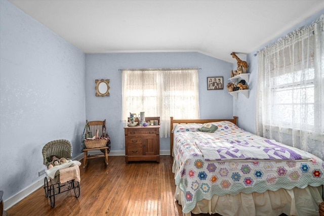 bedroom featuring lofted ceiling, multiple windows, baseboards, and wood finished floors