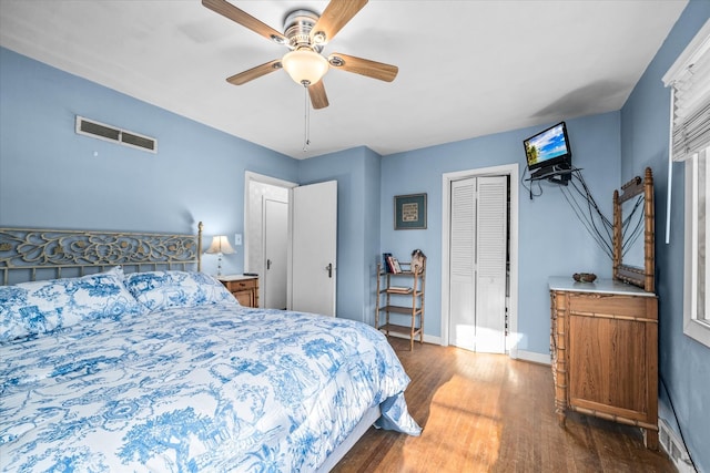 bedroom with baseboards, visible vents, ceiling fan, wood finished floors, and a closet