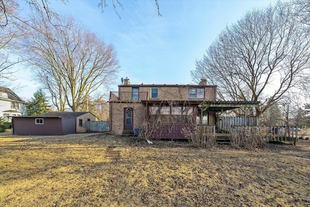 rear view of property with a wooden deck, a chimney, an outdoor structure, and brick siding