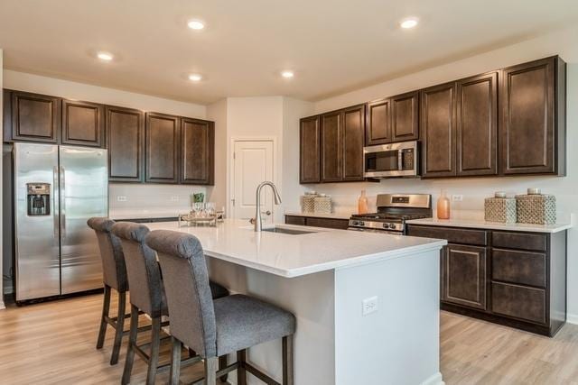 kitchen with stainless steel appliances, a breakfast bar, a sink, and dark brown cabinetry