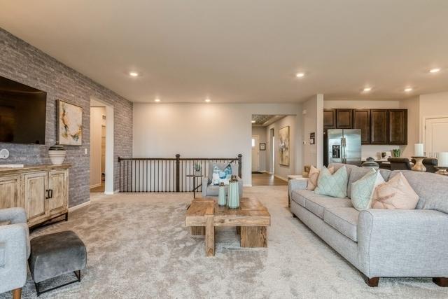 living room with brick wall, light colored carpet, and recessed lighting