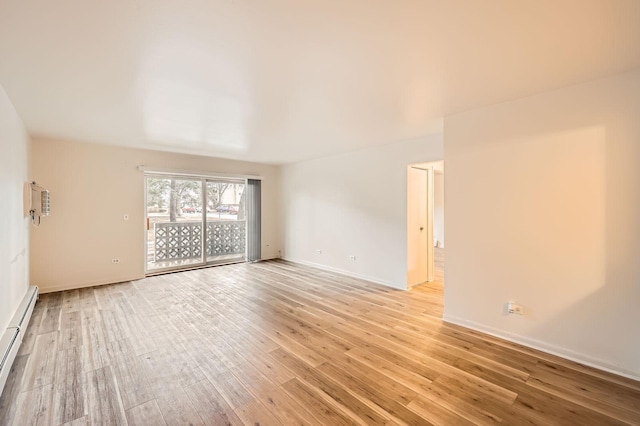 empty room with a baseboard heating unit, light wood-style floors, and baseboards