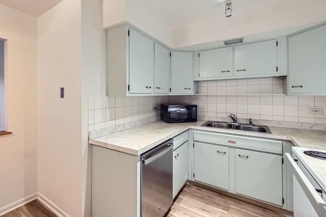 kitchen with black microwave, a sink, light wood-style floors, stainless steel dishwasher, and decorative backsplash