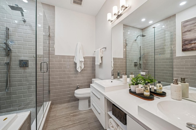 bathroom featuring double vanity, a stall shower, a sink, and tile walls