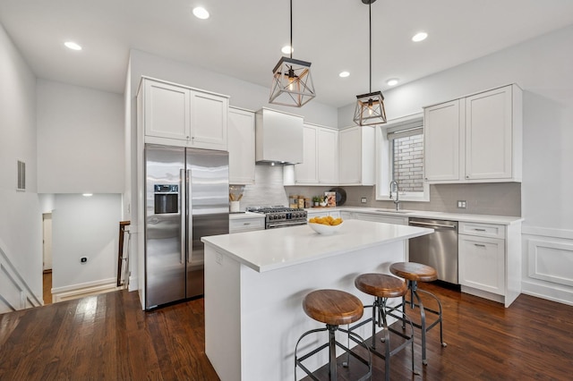 kitchen with a center island, high end appliances, light countertops, visible vents, and a kitchen breakfast bar