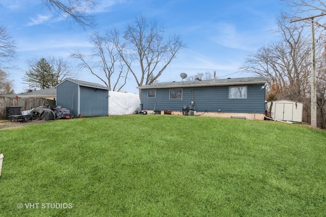 back of house with an outbuilding, a lawn, a storage shed, and fence