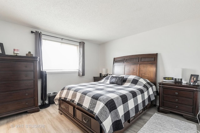 bedroom with a textured ceiling and light wood finished floors