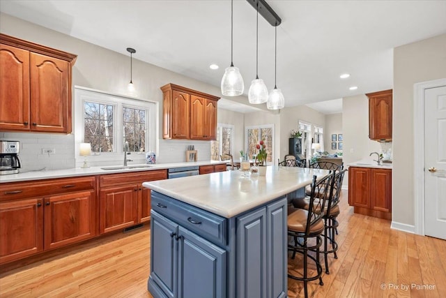 kitchen featuring light wood-style floors, light countertops, a sink, and a kitchen breakfast bar