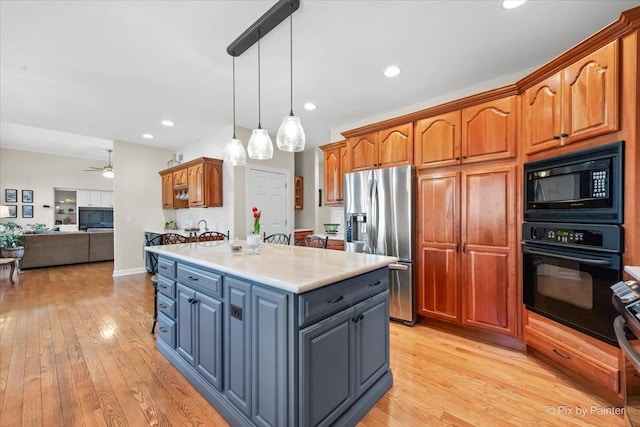 kitchen with light wood-style flooring, a kitchen island, open floor plan, light countertops, and black appliances